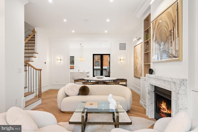 living area featuring recessed lighting, a premium fireplace, visible vents, stairs, and ornamental molding