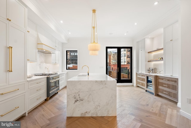 kitchen with range with two ovens, custom range hood, ornamental molding, light stone countertops, and open shelves