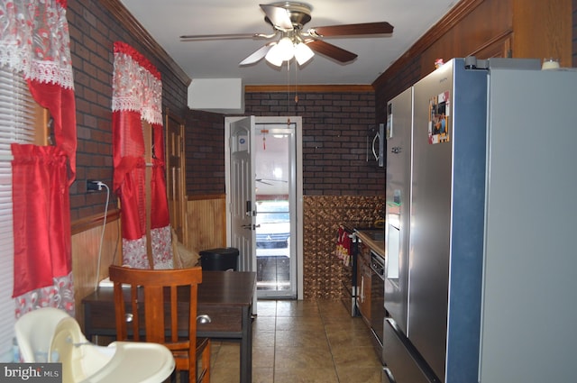 kitchen featuring ceiling fan, dark tile patterned flooring, brick wall, and appliances with stainless steel finishes