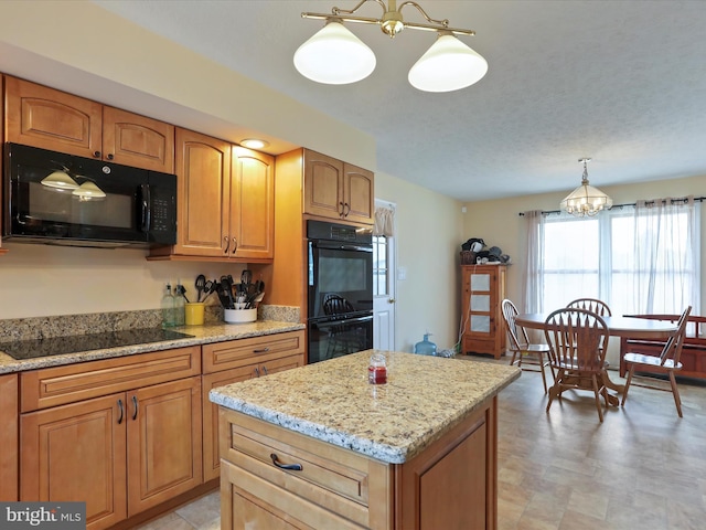 kitchen featuring light stone countertops, a kitchen island, hanging light fixtures, brown cabinets, and black appliances