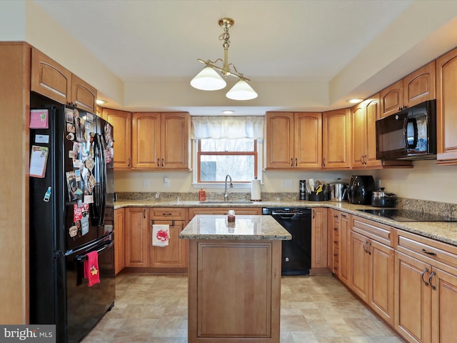 kitchen with light stone counters, a sink, a center island, black appliances, and pendant lighting