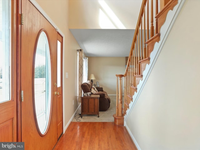 entrance foyer featuring light wood finished floors, stairs, and baseboards