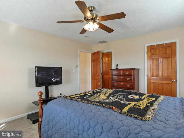 carpeted bedroom with baseboards, visible vents, ceiling fan, and a textured ceiling