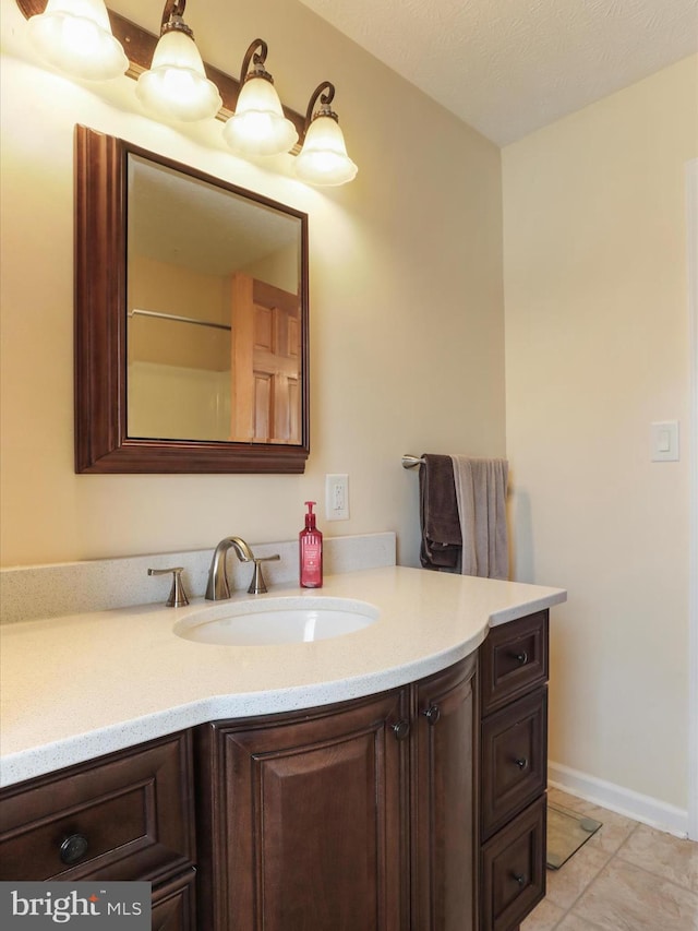 bathroom featuring a textured ceiling, tile patterned flooring, vanity, and baseboards