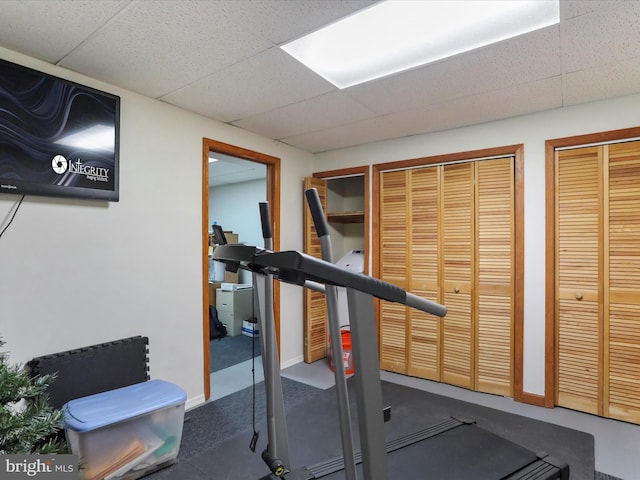 workout area with a paneled ceiling and baseboards