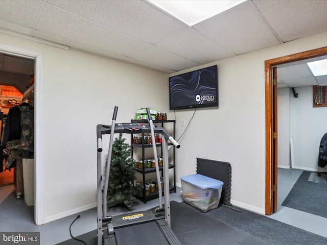 workout area featuring a paneled ceiling and baseboards