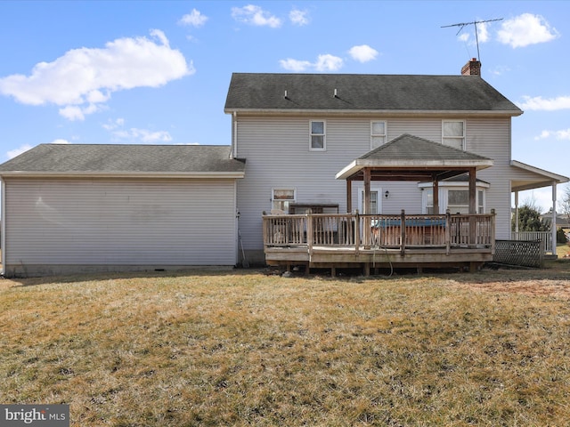 rear view of property featuring a deck, a chimney, and a lawn