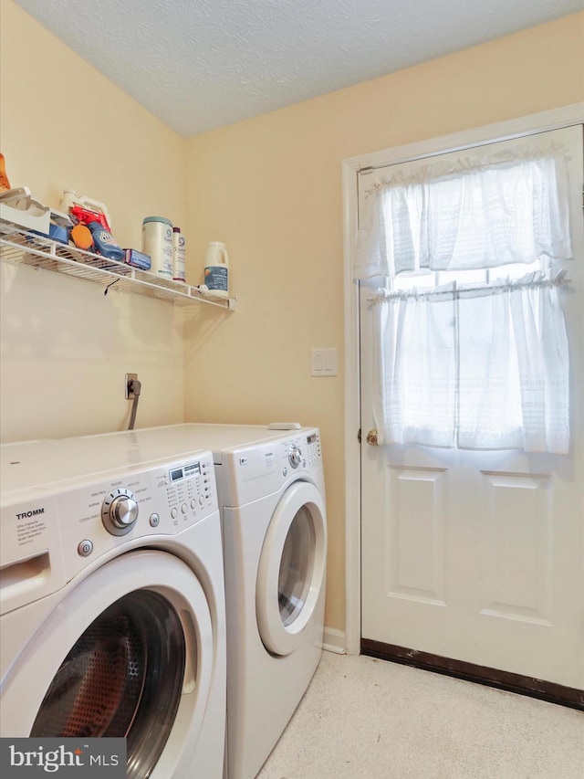 washroom featuring a textured ceiling, laundry area, and washer and clothes dryer