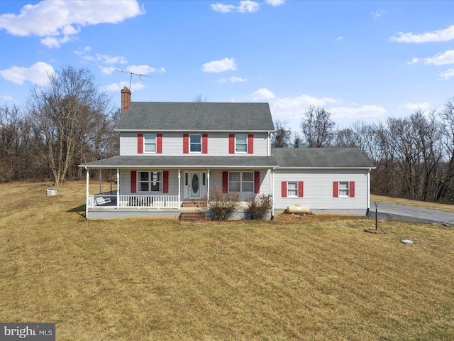 farmhouse-style home with a chimney, a porch, and a front yard