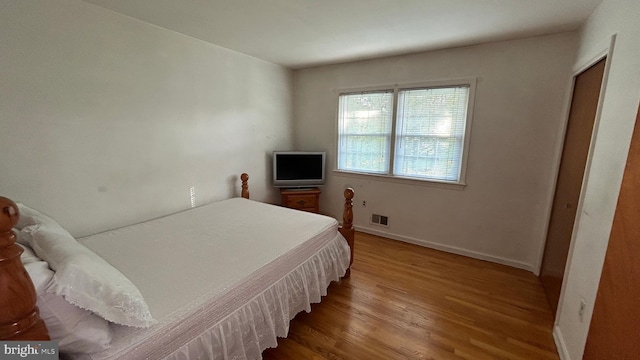 bedroom with visible vents, baseboards, and wood finished floors