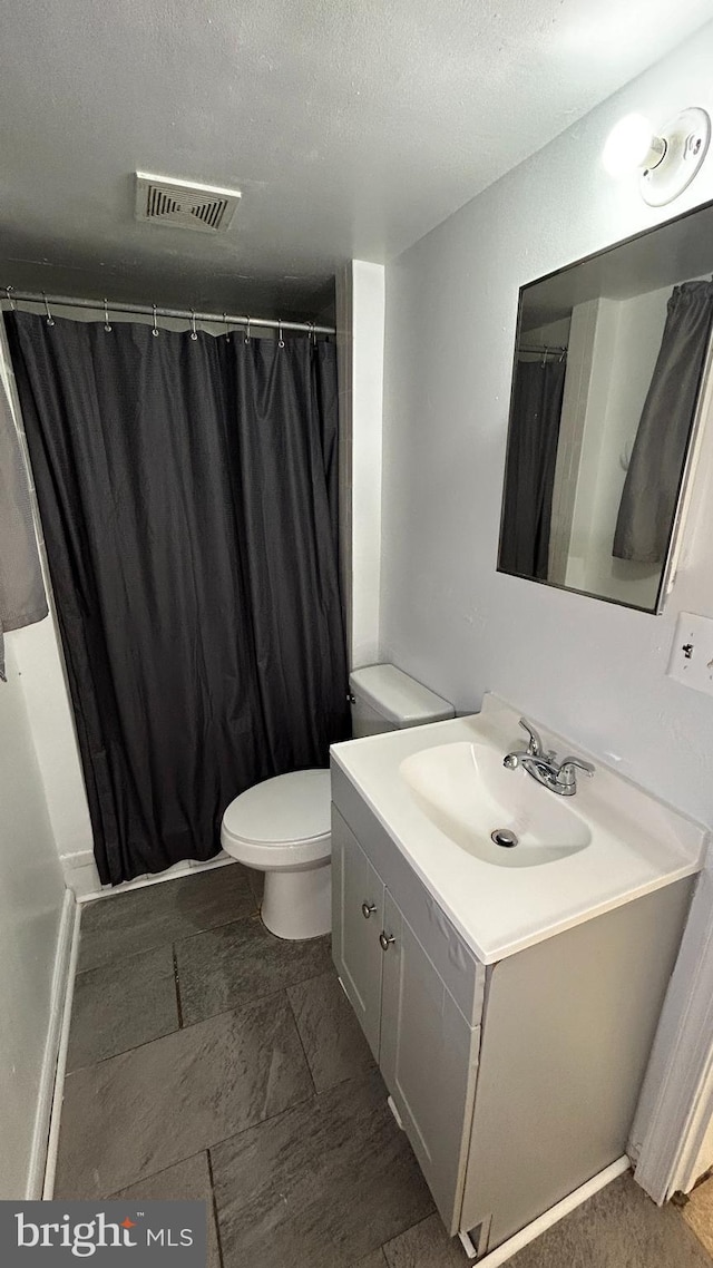 full bath featuring toilet, vanity, a textured ceiling, and visible vents
