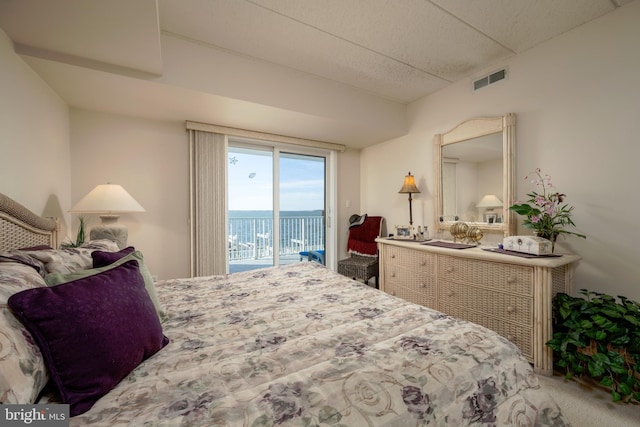 bedroom with a water view, carpet floors, and access to exterior