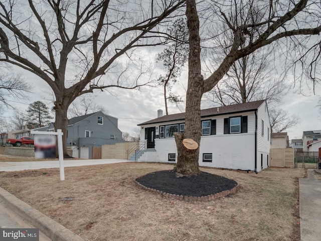 ranch-style home with a chimney, fence, and brick siding