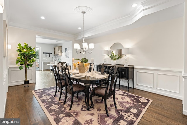 dining space with a chandelier, ornamental molding, dark wood-style flooring, and a decorative wall