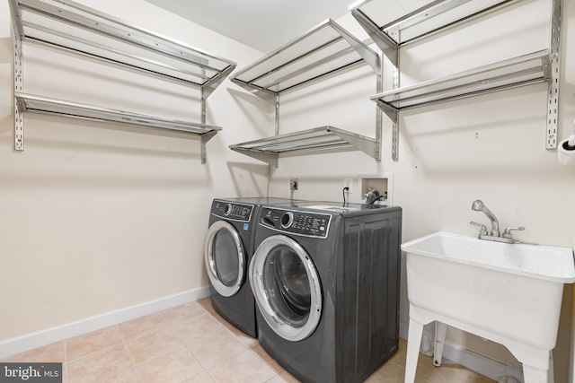 clothes washing area featuring light tile patterned flooring, a garage, laundry area, independent washer and dryer, and baseboards