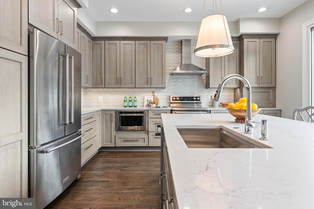 kitchen with dark wood-style floors, wall chimney exhaust hood, appliances with stainless steel finishes, a sink, and backsplash