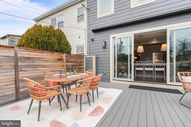 wooden terrace with outdoor dining area and fence