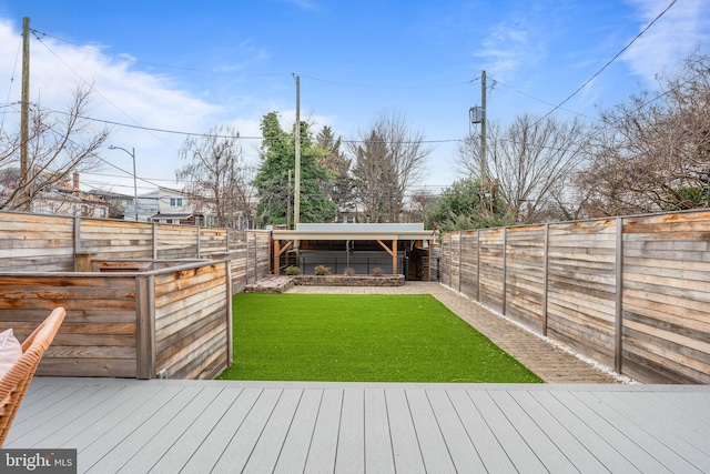 wooden deck featuring a fenced backyard, an outdoor structure, and a yard