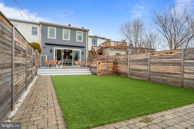 back of house with a fenced backyard, a yard, and a deck