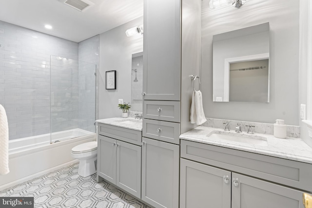 full bath featuring toilet, bath / shower combo with glass door, vanity, and visible vents