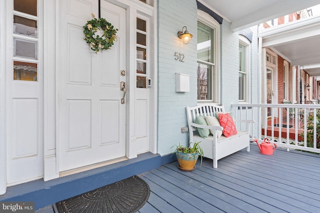 view of exterior entry with covered porch and brick siding