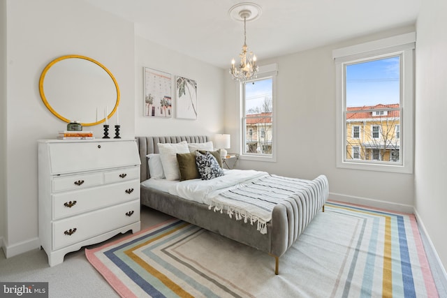 carpeted bedroom featuring a chandelier and baseboards