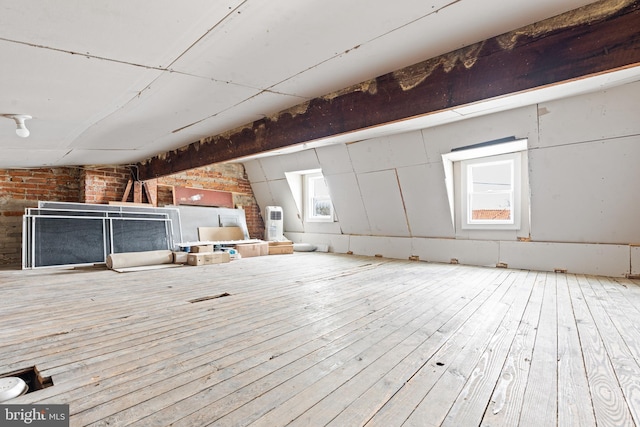 interior space with brick wall and hardwood / wood-style floors