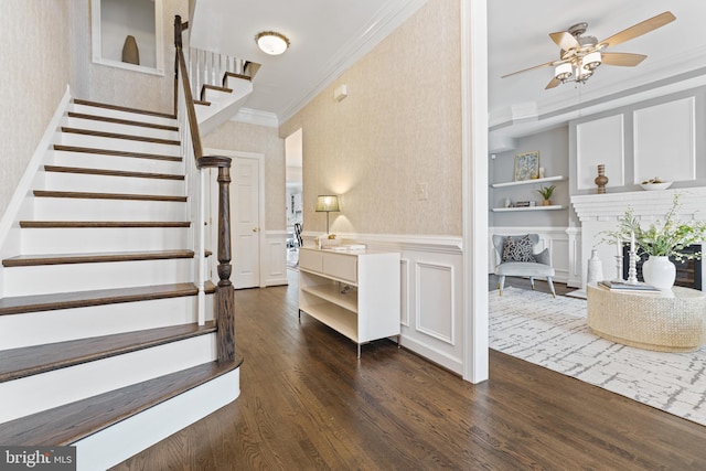 staircase with a decorative wall, wood finished floors, wainscoting, wallpapered walls, and crown molding