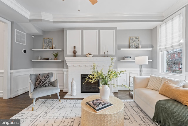 living room with a wainscoted wall, crown molding, visible vents, and wood finished floors