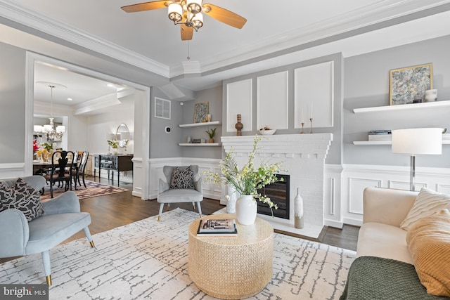 living area with a wainscoted wall, visible vents, a decorative wall, and wood finished floors