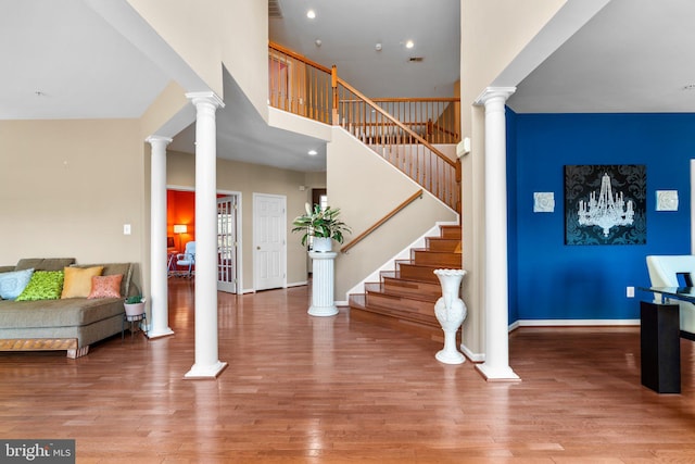 foyer entrance with a high ceiling, light hardwood / wood-style flooring, and ornate columns