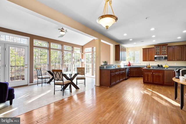 kitchen with appliances with stainless steel finishes, decorative light fixtures, and light wood-type flooring