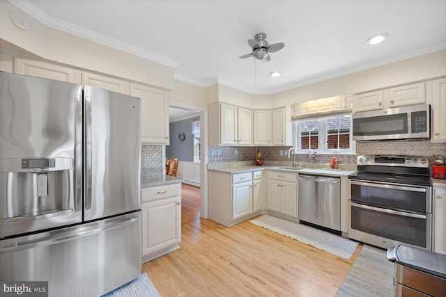 kitchen featuring sink, crown molding, light wood-type flooring, stainless steel appliances, and backsplash