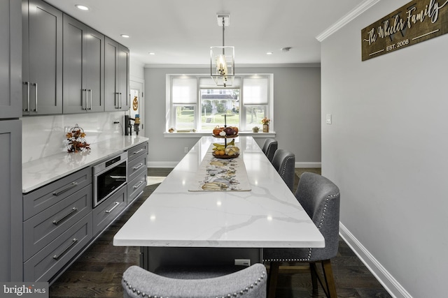 kitchen with a breakfast bar area, gray cabinetry, and decorative light fixtures