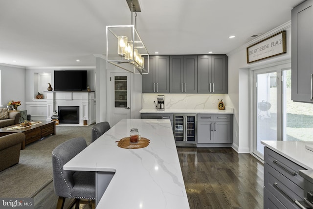 kitchen with a breakfast bar area, gray cabinetry, hanging light fixtures, wine cooler, and ornamental molding