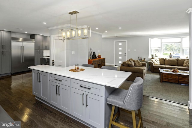 kitchen with gray cabinetry, light stone counters, a kitchen island, and stainless steel built in refrigerator