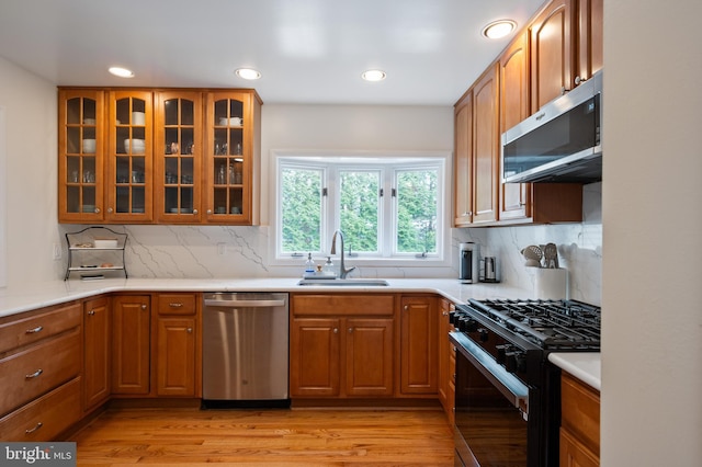 kitchen featuring stainless steel appliances, light wood-type flooring, a sink, and brown cabinets