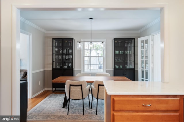 dining area with ornamental molding, light wood-style flooring, and baseboards