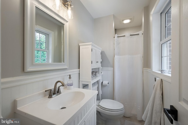 bathroom featuring toilet, a wainscoted wall, a shower with curtain, and vanity