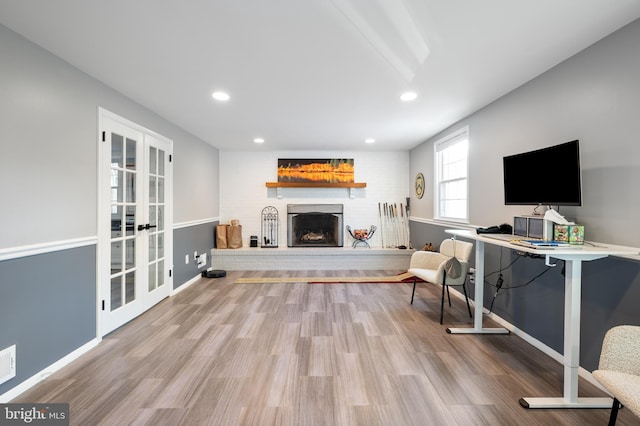 interior space with baseboards, wood finished floors, french doors, a fireplace, and recessed lighting