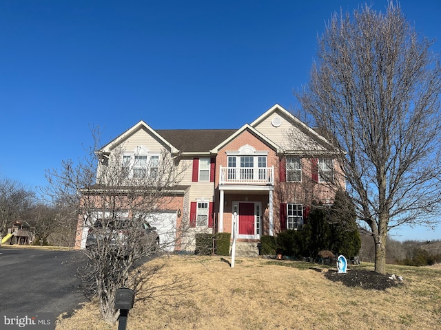 view of front of home featuring driveway, a balcony, an attached garage, a front yard, and brick siding