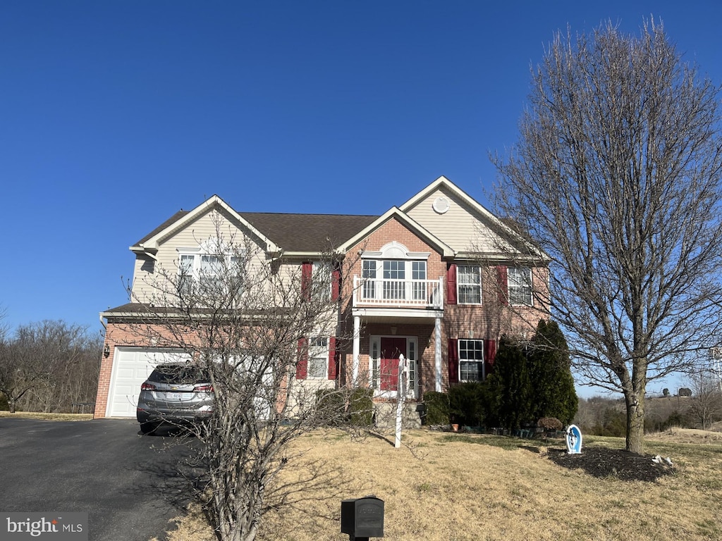 view of front facade with brick siding, a garage, a balcony, and driveway