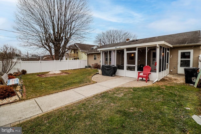 back of property featuring a sunroom and a lawn