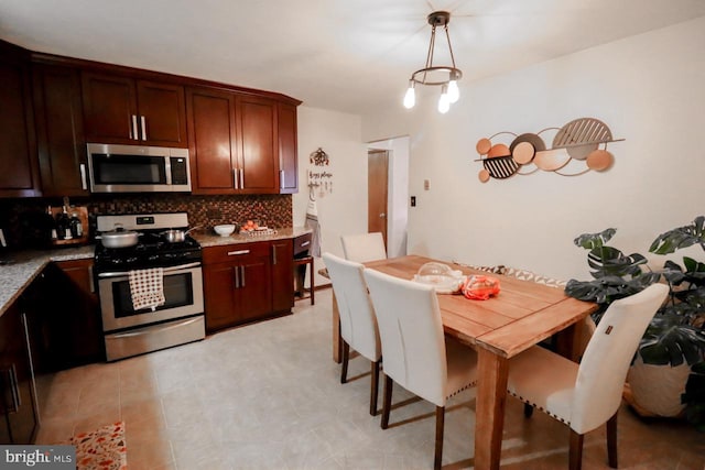 kitchen featuring decorative backsplash, appliances with stainless steel finishes, light stone countertops, and hanging light fixtures