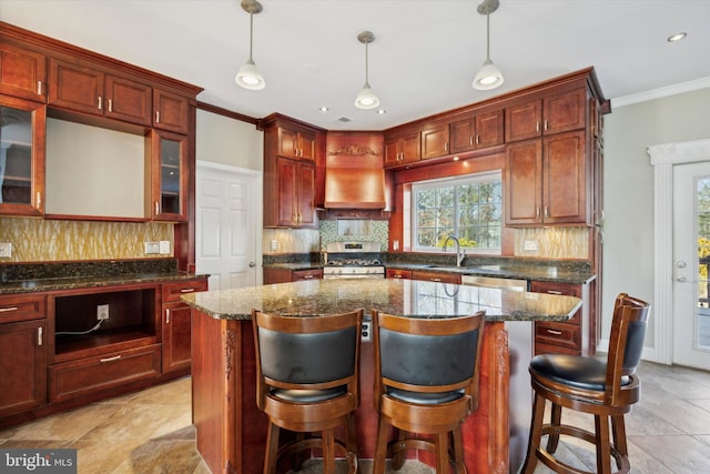 kitchen featuring backsplash, premium range hood, ornamental molding, gas stove, and a sink