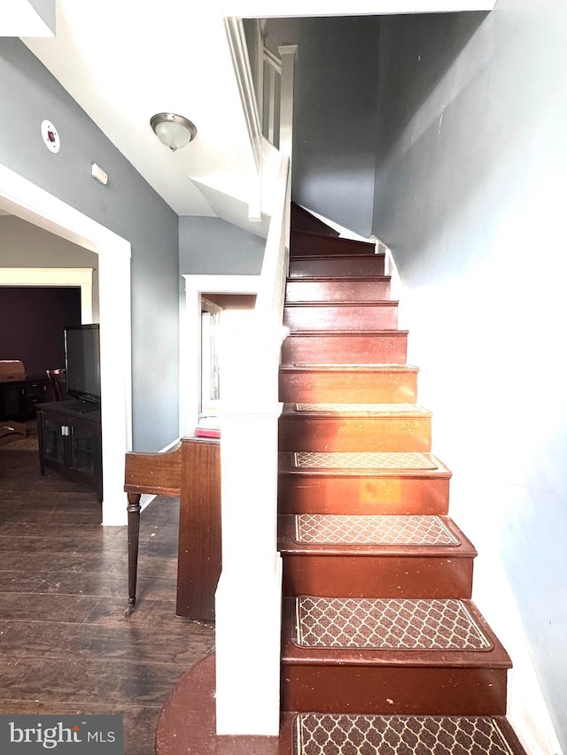 stairway with lofted ceiling and hardwood / wood-style floors