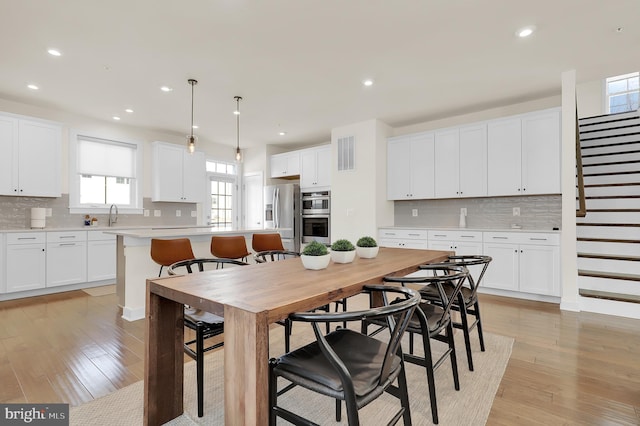 dining space featuring light wood-style floors, stairway, visible vents, and recessed lighting