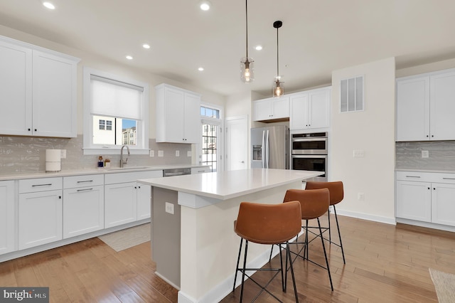 kitchen with stainless steel appliances, white cabinets, light countertops, and visible vents