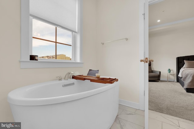 ensuite bathroom with marble finish floor, ensuite bath, baseboards, and a freestanding tub