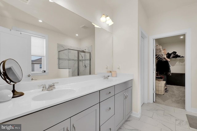 bathroom featuring marble finish floor, a walk in closet, a sink, and a stall shower